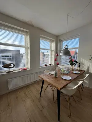 a dining room with a table and chairs and windows at Authentic sunny Amsterdam Jordaan apartment in Amsterdam