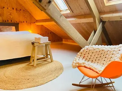 a attic room with a bed and a chair at De Wagenloods in Alphen aan den Rijn