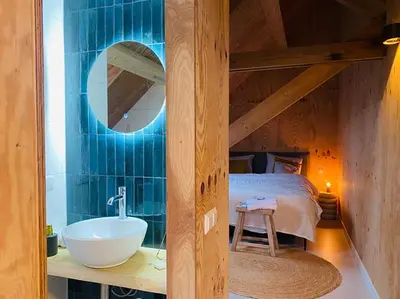 a bathroom with a sink and a bed and a mirror at De Wagenloods in Alphen aan den Rijn