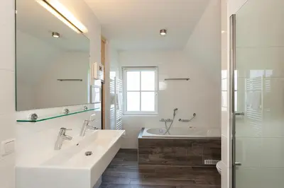 a white bathroom with a tub and a sink at Buitenplaats Witte Raaf aan Zee in Noordwijk