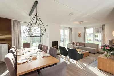a dining room and living room with a table and chairs at Buitenplaats Witte Raaf aan Zee in Noordwijk
