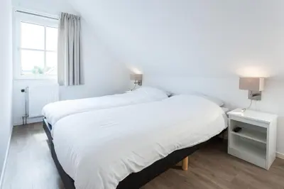 a bedroom with two beds and a window at Buitenplaats Witte Raaf aan Zee in Noordwijk