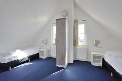 a bedroom with two beds and two windows at Buitenplaats Witte Raaf aan Zee in Noordwijk