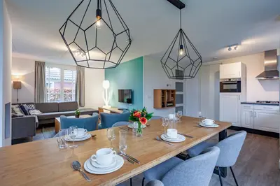 a dining room and living room with a table and chairs at Buitenplaats Witte Raaf aan Zee in Noordwijk