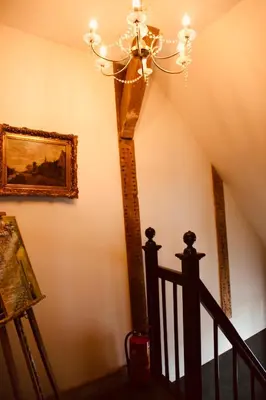 a staircase with a chandelier and a painting on the wall at Herberg De Hollandsche Leeuw in Nieuwkoop