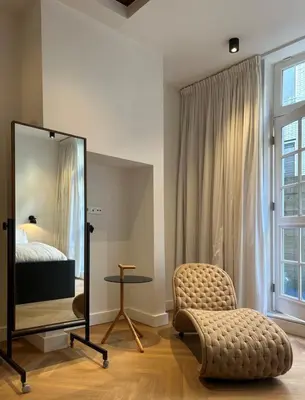 a bedroom with a mirror and a chair and a bed at The Design apartment with canal-view in Amsterdam