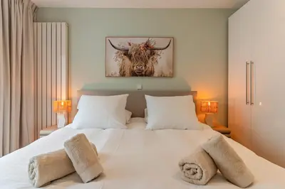 a bedroom with a bed with a bull painting on the wall at Appartement de Burgemeester - centrum in Castricum