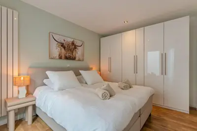 a bedroom with a large white bed with white cabinets at Appartement de Burgemeester - centrum in Castricum