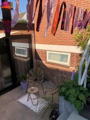 a patio with two chairs and ties hanging from a brick building at Logies at the sea in Katwijk aan Zee