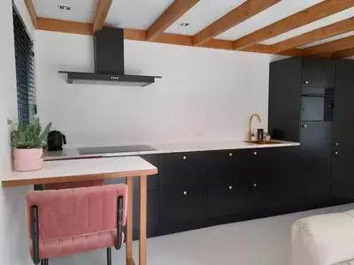 a kitchen with black cabinets and a pink chair at Logies at the sea in Katwijk aan Zee