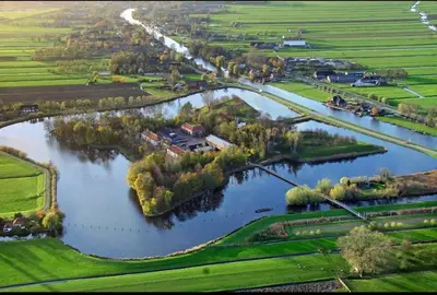 an aerial view of a river with a house and trees at Romantic jacuzzi suite in the city center in Bodegraven