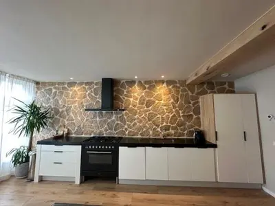 a kitchen with white cabinets and a black stove at Romantic jacuzzi suite in the city center in Bodegraven