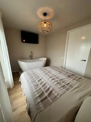 a bedroom with a bed and a tub and a sink at Romantic jacuzzi suite in the city center in Bodegraven