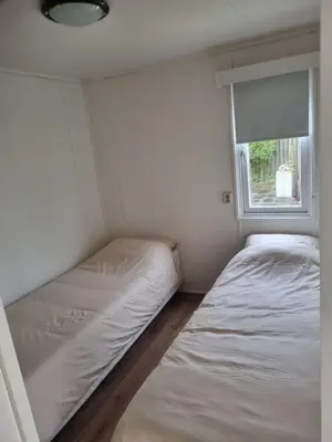 two beds in a small room with a window at Family Friendly Holiday Chalet with Pool in Holiday Park in Opmeer