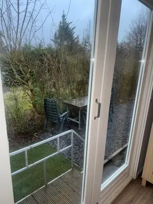 a door leading to a patio with a table and chairs at Family Friendly Holiday Chalet with Pool in Holiday Park in Opmeer