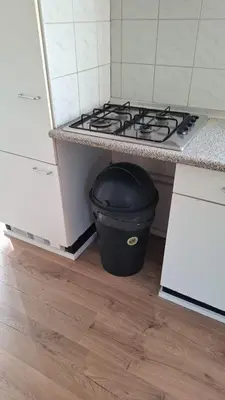 a black trash can sitting under a stove in a kitchen at Family Friendly Holiday Chalet with Pool in Holiday Park in Opmeer