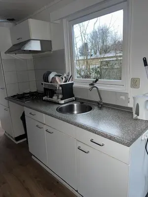 a kitchen with a sink and a window at Family Friendly Holiday Chalet with Pool in Holiday Park in Opmeer