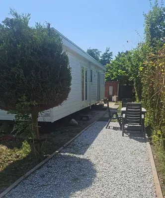 a white caravan with a table and chairs in a yard at Family Friendly Holiday Chalet with Pool in Holiday Park in Opmeer