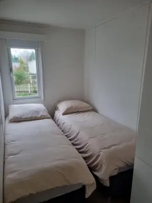 two beds in a room with a window at Family Friendly Holiday Chalet with Pool in Holiday Park in Opmeer