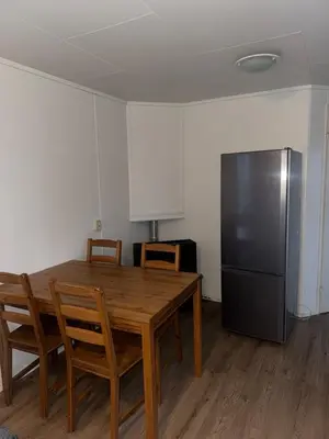 a kitchen with a wooden table and a refrigerator at Family Friendly Holiday Chalet with Pool in Holiday Park in Opmeer