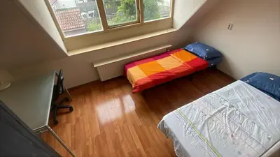 a small room with two beds and a window at C-Home in Utrecht