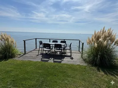 a table and chairs sitting on a deck overlooking the water at Villa Sea Side am Markermeer Modernes Waterfront Haus 6 Pers in Bovenkarspel