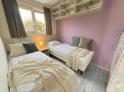 a small bedroom with two beds and a window at Villa Sea Side am Markermeer Modernes Waterfront Haus 6 Pers in Bovenkarspel