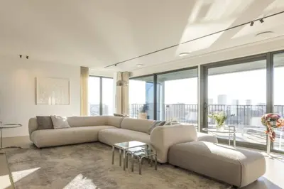 a living room with a large couch and some windows at Super View Penthouse Deluxe in Amsterdam