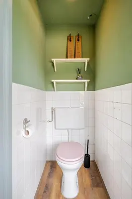 a bathroom with a pink toilet and green walls at Bij Parels landelijk overnachten in het groen in Velserbroek