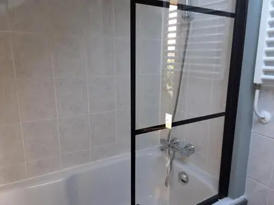 a bathroom with a bath tub with a glass shower door at Bij Parels landelijk overnachten in het groen in Velserbroek