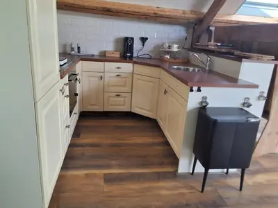 a kitchen with white cabinets and a wooden floor at Bij Parels landelijk overnachten in het groen in Velserbroek