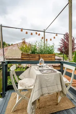 a table and chairs on the deck of a house at Bij Parels landelijk overnachten in het groen in Velserbroek