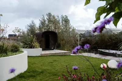 a garden with a black shed with purple flowers at 8 persons Wellness Villa Tulpenacker in Roelofarendsveen