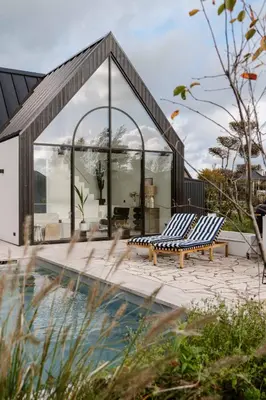 a house with a pool and two lounge chairs at 8 persons Wellness Villa Tulpenacker in Roelofarendsveen