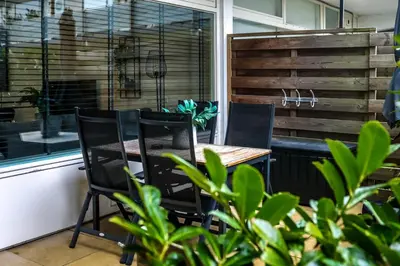 a patio with a table and chairs and a window at Amsterdam Beach Home 88 in Zandvoort
