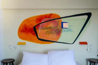 a mirror on a wall above a bed with two stools at Pension Homeland in Amsterdam