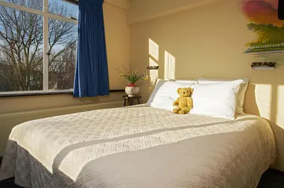 a teddy bear sitting on a bed in a bedroom at Pension Homeland in Amsterdam