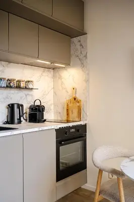 a kitchen with white cabinets and a stove top oven at Green Heart Apartment Private Parking in Zandvoort