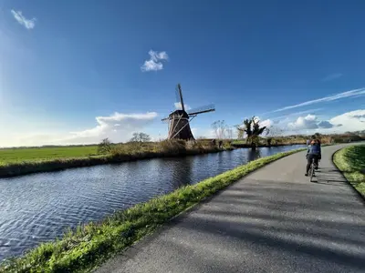 a person riding a bike on a path next to a windmill at Natuurhuisje Abcoude - Groen Verblijf Buitenhuis in Abcoude