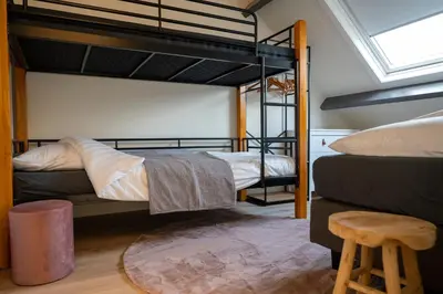 a bedroom with two bunk beds and a stool at 10 persons Tulpenacker Comfort in Roelofarendsveen