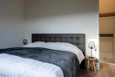 a bedroom with a large bed with a gray headboard at 10 persons Tulpenacker Comfort in Roelofarendsveen