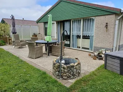 a patio with a table and an umbrella and a fire pit at Ferienhaus Müller in Burgerbrug