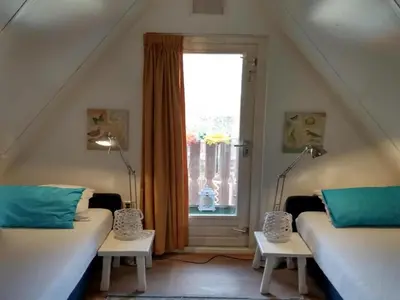 a attic room with two beds and a window at Cozy holiday home in Burgerbrug in Burgerbrug