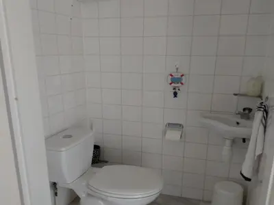 a white bathroom with a toilet and a sink at Cozy holiday home in Burgerbrug in Burgerbrug
