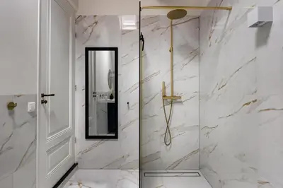 a bathroom with white marble walls and a glass shower at Luxury Studio in Utrecht Center - view on canal in Utrecht