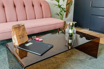a pink couch and a table with bottles of wine at Luxury Spacious Studio in Utrecht City Center in Utrecht