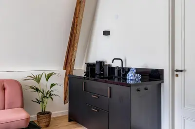 a black cabinet with a sink and a pink chair at Luxury Spacious Studio in Utrecht City Center in Utrecht