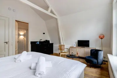 a bedroom with a white bed and a living room at 2 Luxurious Studios in Utrecht City Center in Utrecht