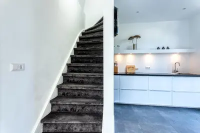 a staircase in a house with white cabinets and a kitchen at Casa Vos Family Home in Zandvoort