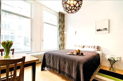 a bedroom with a bed and a table and window at AibarResidentieJH in Amsterdam